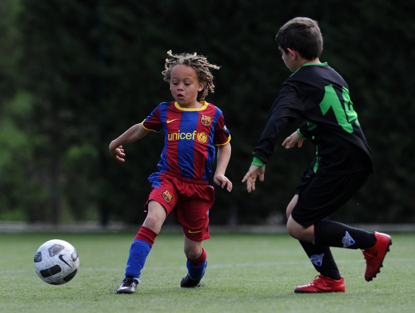 Young boy in a FC Barcelona jersey playing soccer.