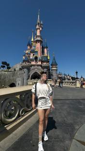 a woman stands in front of the disney castle
