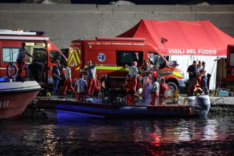 Rescue workers at night near a boat after a sailboat sank.