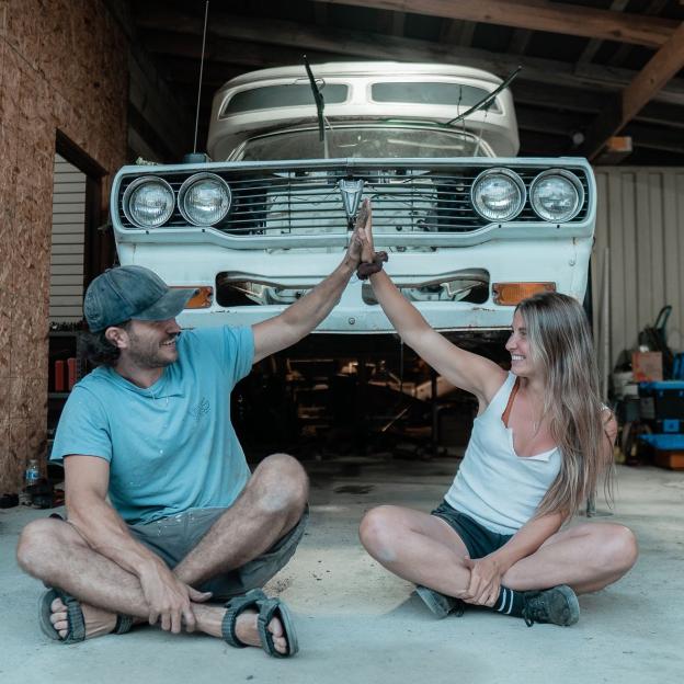 Couple high-fiving in front of a classic car.