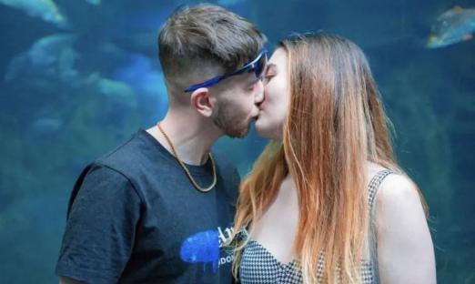 Couple kissing in front of an aquarium.