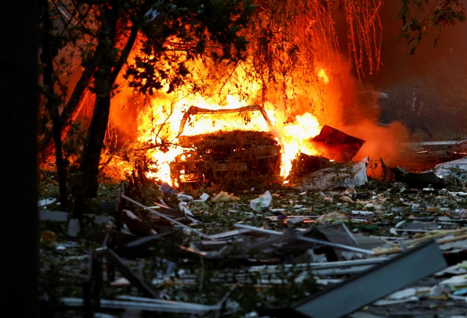 Burning car amid debris from Russian missile and drone strikes in Kyiv.