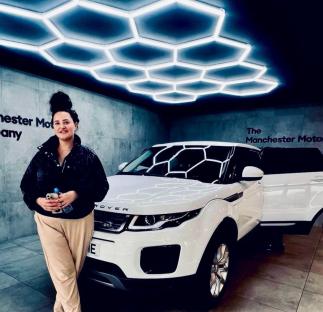 Woman standing next to her white Range Rover.