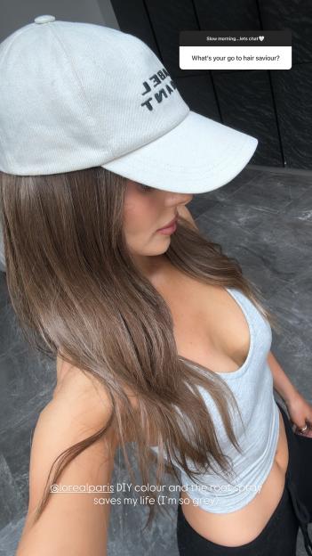 Woman with long brown hair wearing a baseball cap, recommending L'Oréal Paris hair color.