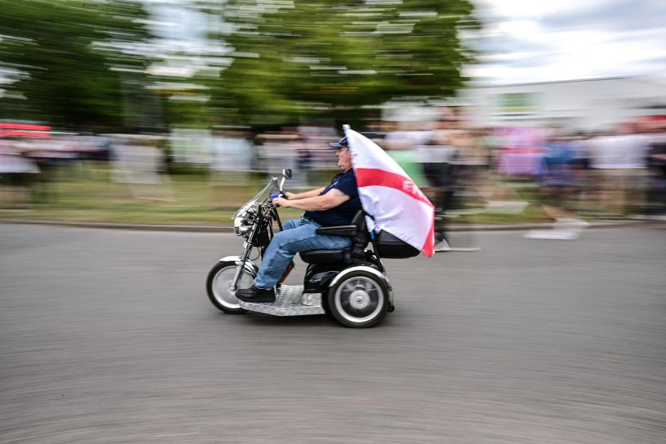 A demonstrator on an electric scooter carries a St. George's Cross flag at an anti-immigration protest.