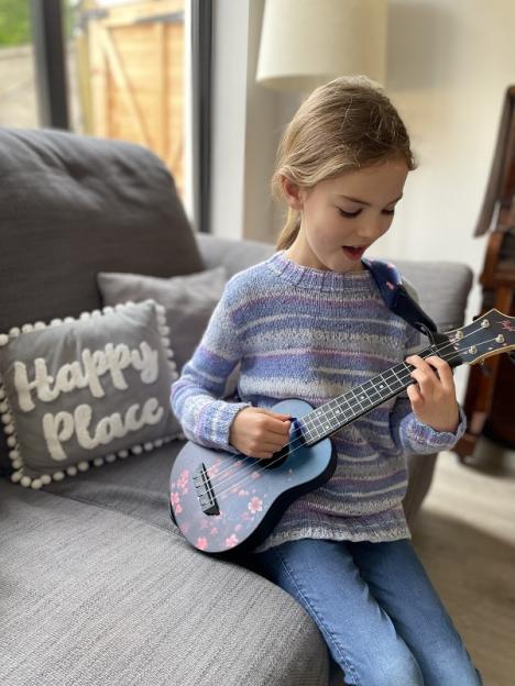 Emily Smith playing a blue ukulele with pink cherry blossoms.