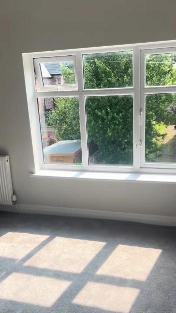 Sunlight streams through a window in a room with grey carpeting.