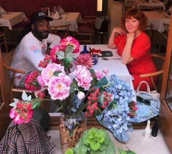 Couple sitting at a restaurant table with a large floral arrangement in front of them.