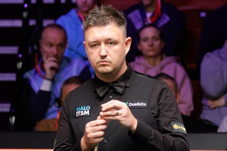 Kyren Wilson chalking his cue at a snooker match.