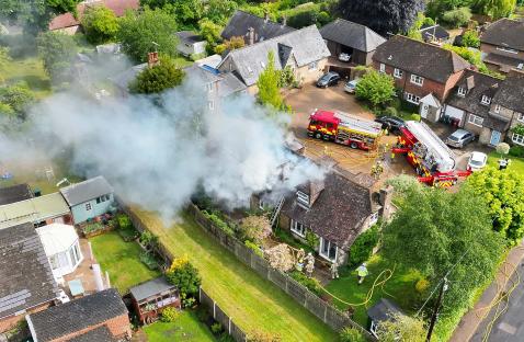 Aerial view of firefighters extinguishing a house fire.