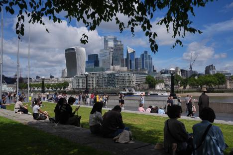 People relaxing in a London park with the city skyline in the background.