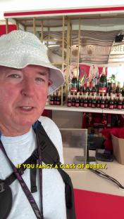 Man in bucket hat at bar with many bottles of champagne.