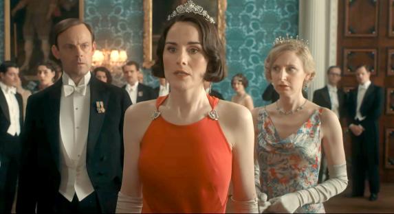 Scene from Downton Abbey featuring women in formal gowns and men in tuxedos.
