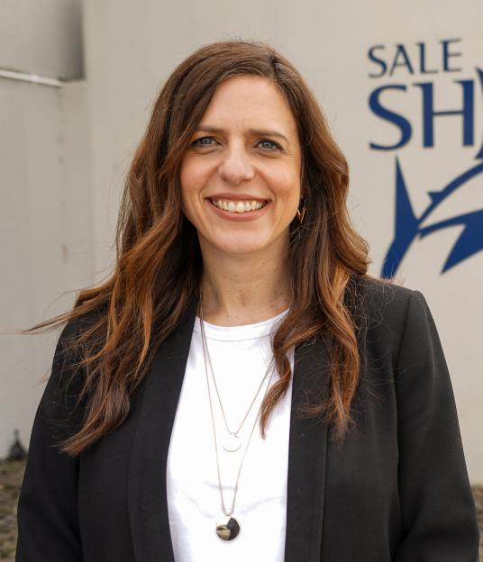 Portrait of Claire Banbury in front of a Sale Sharks logo.