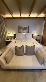 Hotel room with a bed and couch, welcome back message on the bed.