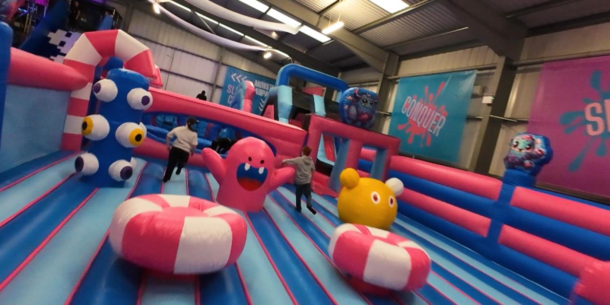 People running on a bouncy obstacle course with inflatable monster characters.