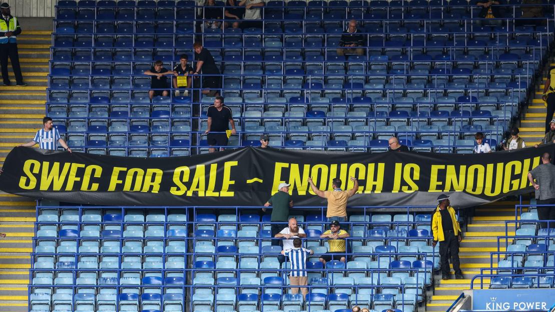 Fans holding a banner that reads "SWFC FOR SALE - ENOUGH IS ENOUGH" at a football match.