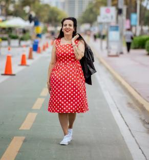 Woman in red polka dot dress walking down a street.