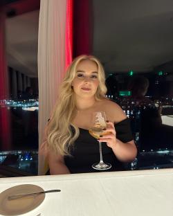 a woman in a black dress is holding a glass of wine