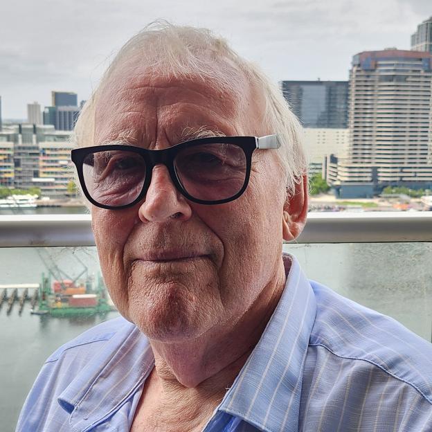 Portrait of Paul Mullen, a forensic psychiatrist, looking towards the camera, with a city skyline in the background.