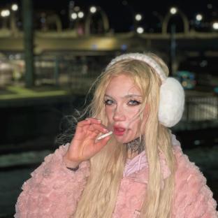 Photo of a blonde woman smoking a cigarette.