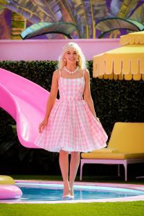 Margot Robbie as Barbie in a pink gingham dress by the pool.