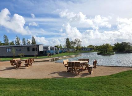 Picnic tables by a lake at Mill Rythe Holiday Park.
