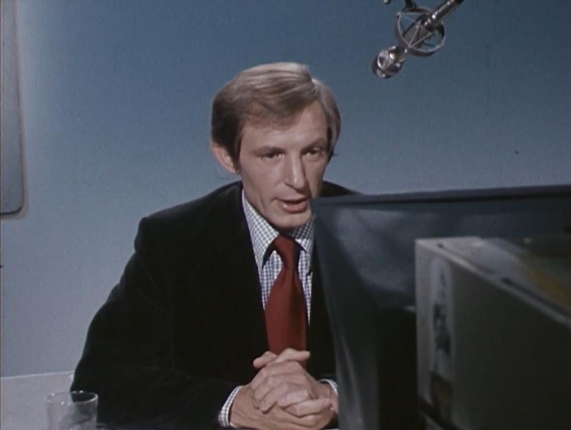 Man in suit speaking into microphone.