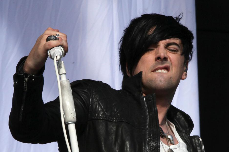 Ian Watkins, lead singer of Lostprophets, performing on stage with a microphone.