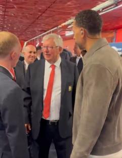 Sir Alex Ferguson speaking with other men in suits.