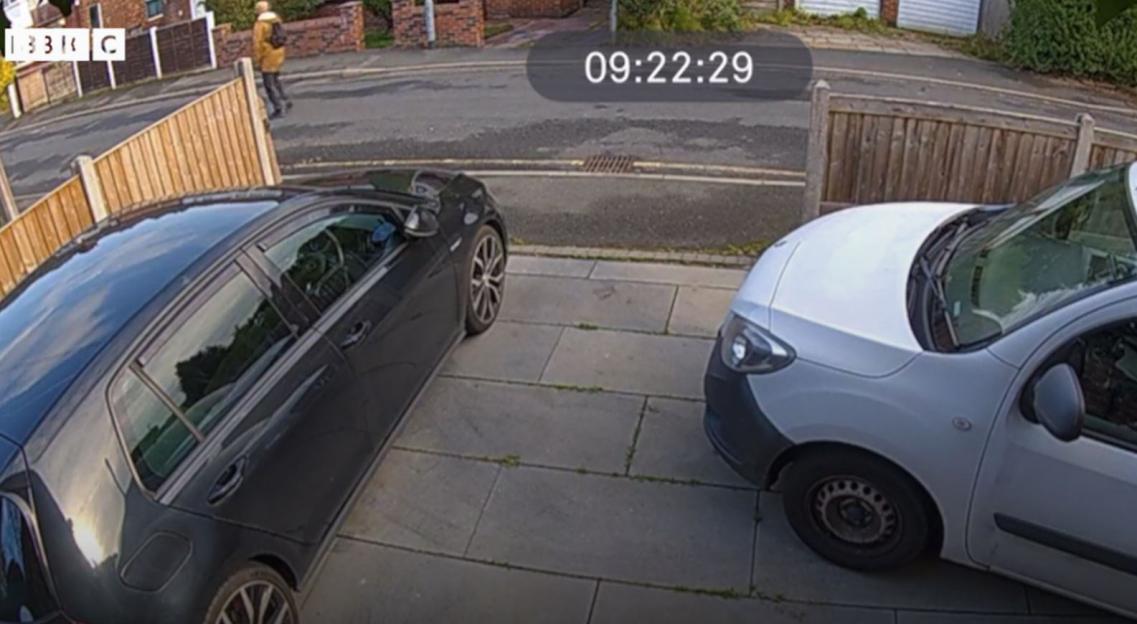 Man walking on a street as recorded by a doorbell camera at 09:22:29, with two cars parked in the foreground.