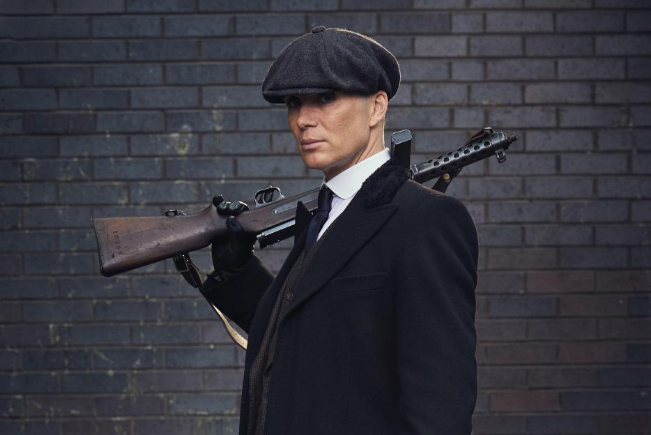 Cillian Murphy as Tommy Shelby from Peaky Blinders, carrying a submachine gun.
