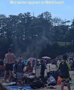 Mini twister on a Welsh beach, beachgoers watching.