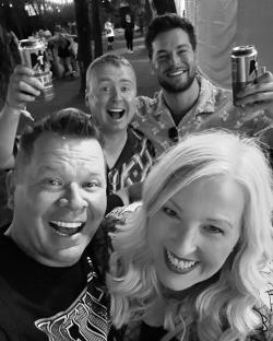 Black and white photo of four people smiling and holding drinks.