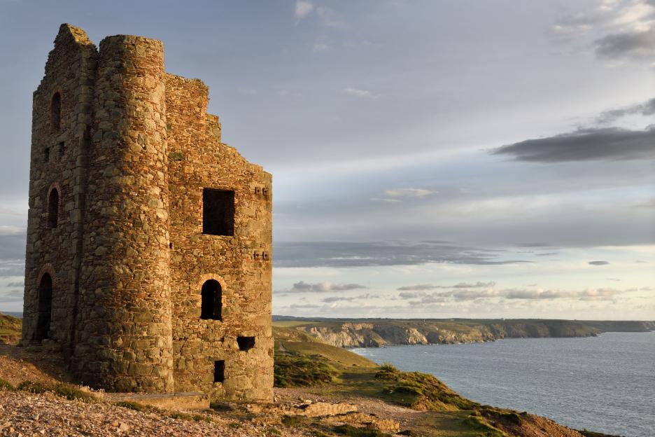 Abandoned Stamps and Whim Engine house at Wheal Coates tin mine on the Celtic Sea Cornwall England with RAF Portreath on cliff tops