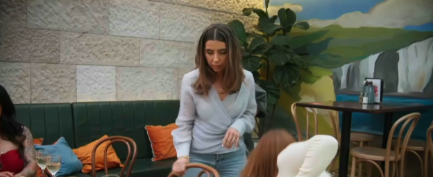 Woman in light blue top setting the table at a restaurant.