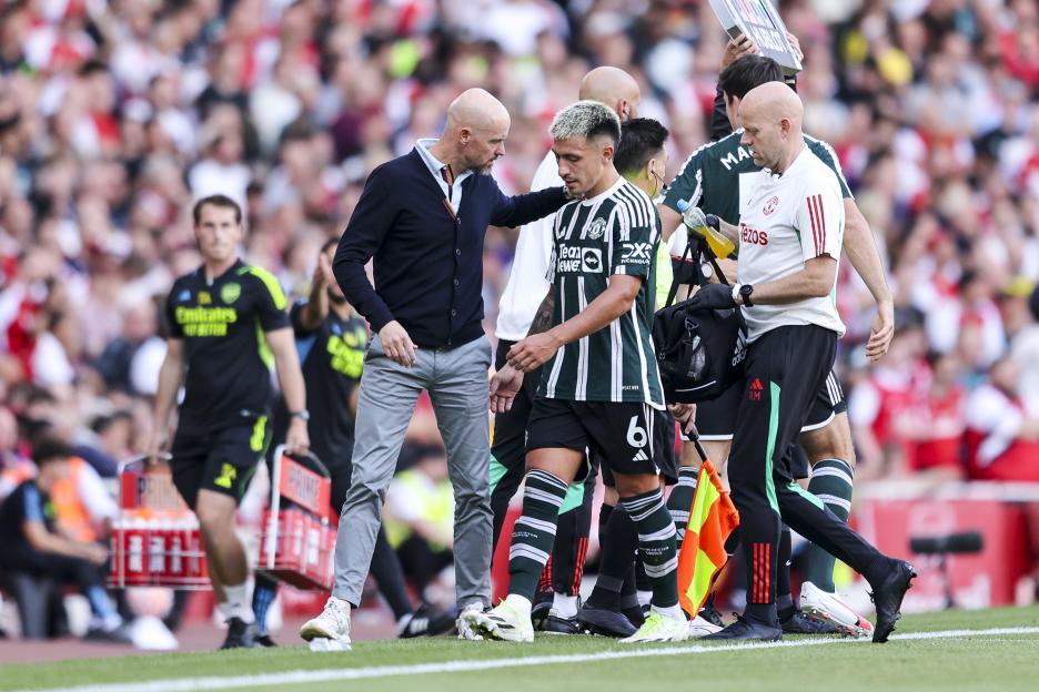 Lisandro Martínez being subbed off due to injury with Coach Erik ten Hag during a soccer match.
