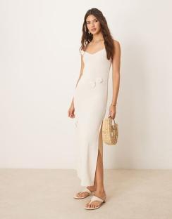 Woman in a cream maxi dress with floral accents.