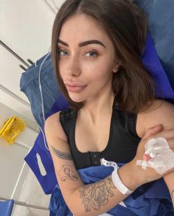 Woman in hospital bed recovering from breast augmentation surgery.