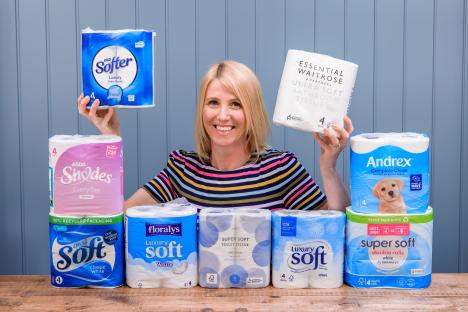 Woman holding various brands of toilet paper.