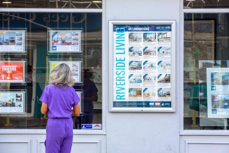 Woman looking at real estate listings in a London storefront.