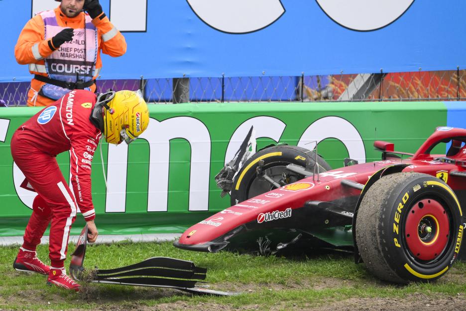 Lewis Hamilton examining the damaged front wing of his Ferrari after a crash.