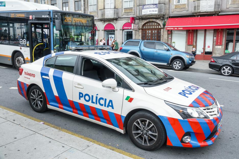 Portuguese police car parked on a city street.