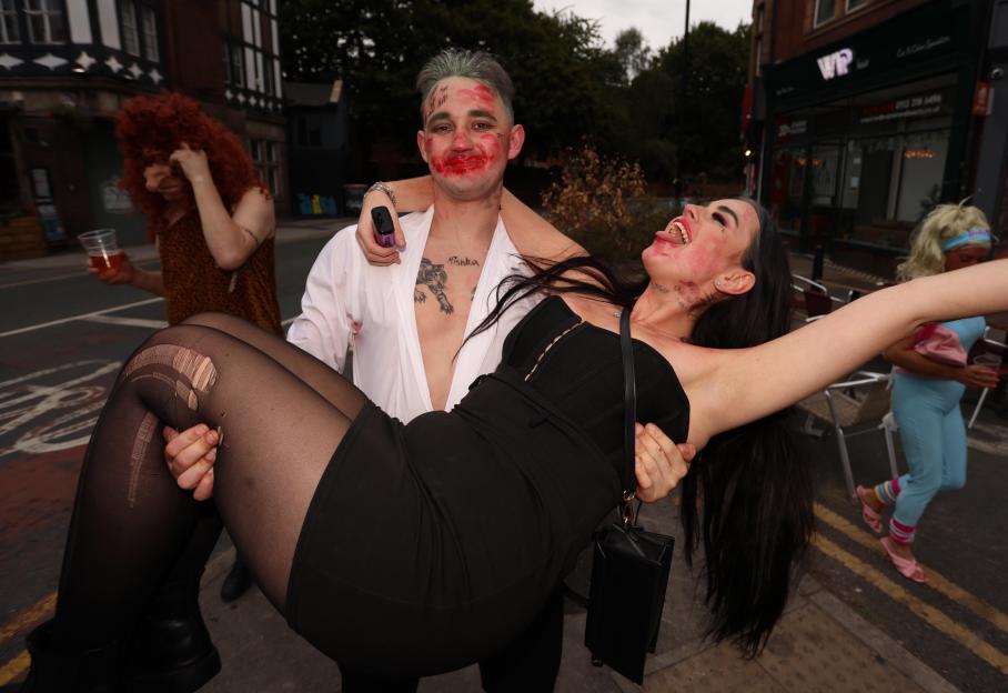 A man carrying a laughing woman during a pub crawl.