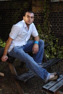 Photo of Paul Danan sitting on a park bench.