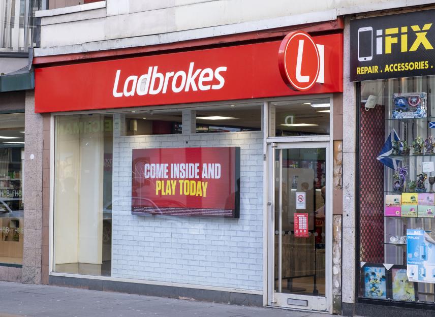 A Ladbrokes betting shop with a digital sign advertising "Come Inside and Play Today".