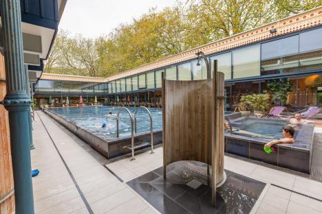 Outdoor pool and hot tub with people swimming and relaxing.