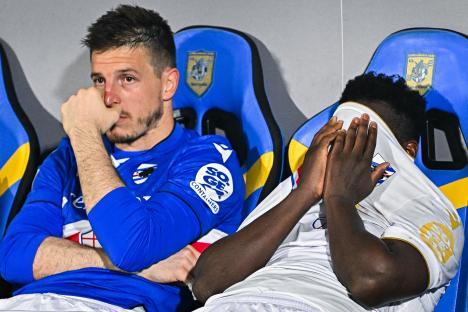 Two Sampdoria soccer players sitting dejectedly after their team's relegation.