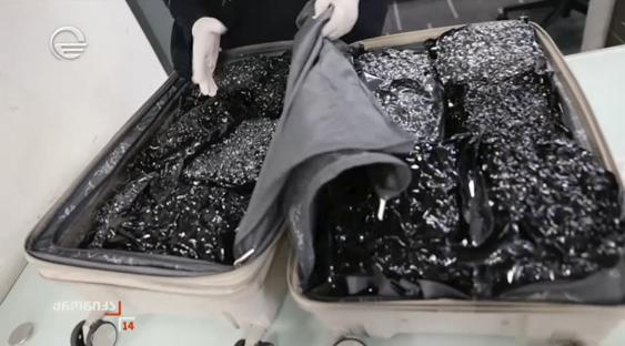 Suitcase filled with black packages.