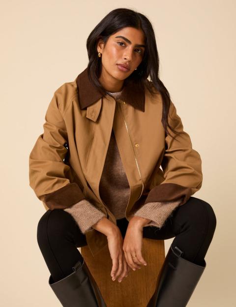 Woman wearing a tan jacket and black pants.